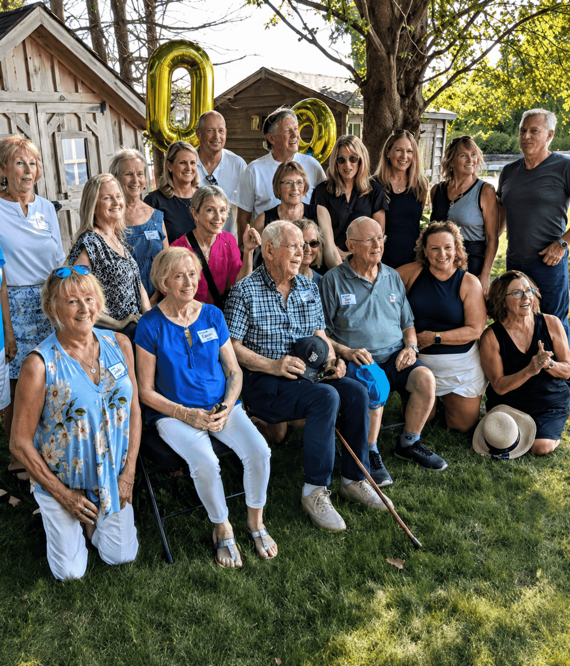 Large family gathered on a lawn in front of gold number 90 balloons